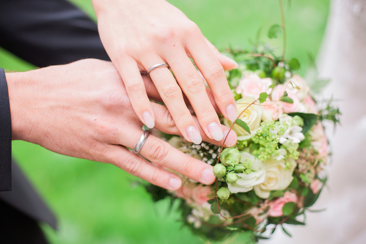 Hände Eherpaar mit Ringen und Brautstrauß